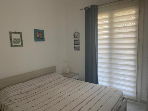 una camera con un letto e una finestra con un'otturatore di Casa Moro a Trinità dʼAgultu