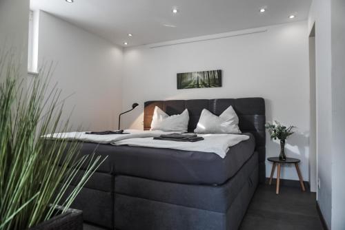 a bedroom with a black bed with white pillows at Neu gebautes Apartment mit Sonnenterasse in der Nähe vom Siebengebirge & Bonn in Königswinter