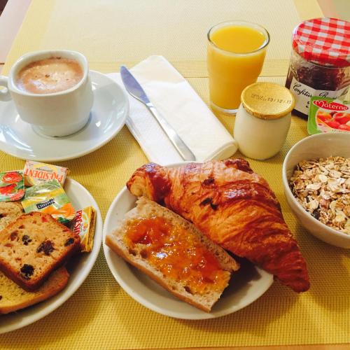 a table with plates of breakfast food and a cup of coffee at Résidence Thibaud in Toulouse