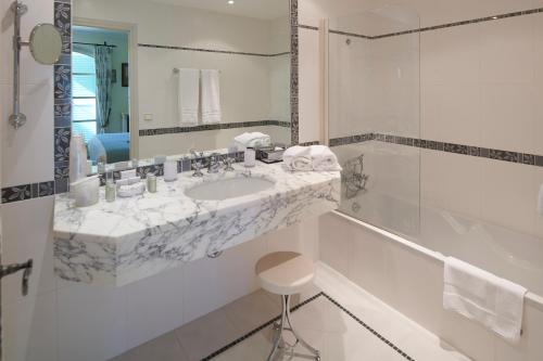 La salle de bains blanche est pourvue d'un lavabo et d'une baignoire. dans l'établissement Hôtel La Grande Bastide, à Saint-Paul-de-Vence