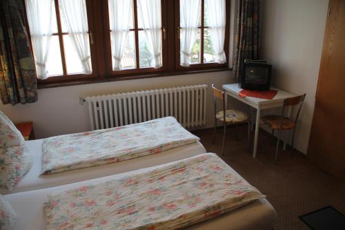 a bedroom with two beds and a table with a television at Pension Becker in Rothenburg ob der Tauber