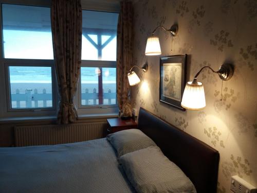 a bedroom with two lights on the wall and a bed at Beachcomber in Swansea