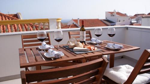 a wooden table with wine glasses and food on a balcony at Ana's Apartments in Sines
