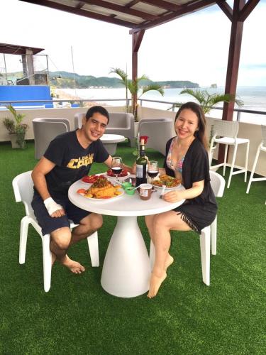 a man and woman sitting at a table with food at Hotel Andy in Atacames