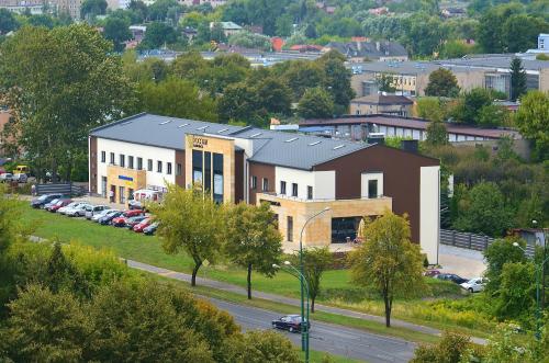 a building with a lot of cars parked in a parking lot at Hotel Pogoria Residence in Dąbrowa Górnicza