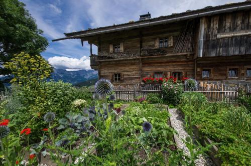 an old wooden house with flowers in front of it at Alpengasthof Hochsöll in Söll