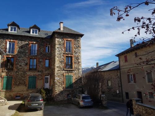 - un grand bâtiment en pierre avec des voitures garées devant dans l'établissement Grand appartement 130m2 à 5mn des stations de ski, à Formiguères