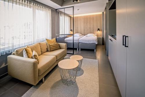 a living room with a couch and a bed at Apart! & Moment! in De Haan