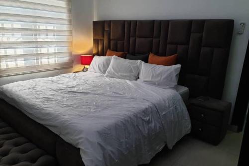 um quarto com uma cama grande e uma grande cabeceira. em Well furnished and spacious 2 bedroom apartment em Abuja