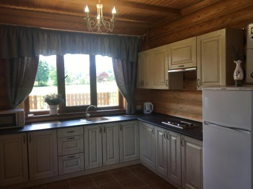 a kitchen with white cabinets and a large window at Cottage Simka in Mykulychyn