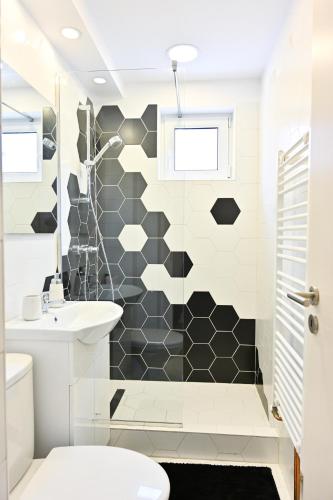 a bathroom with a black and white tiled wall at Sophia's Cozy Apartment in Mediaş