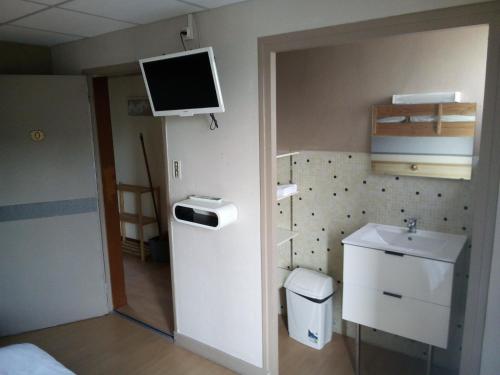 a small bathroom with a sink and a tv on the wall at Hotel du Lac - Au Bord du Lac in La Tour-dʼAuvergne