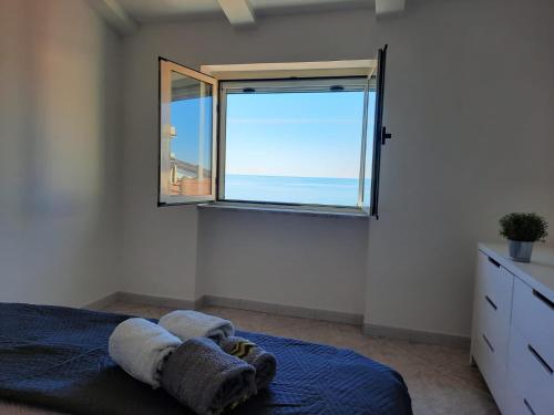 een slaapkamer met een raam met uitzicht op de oceaan bij Petra Marina Aurora in Pisciotta