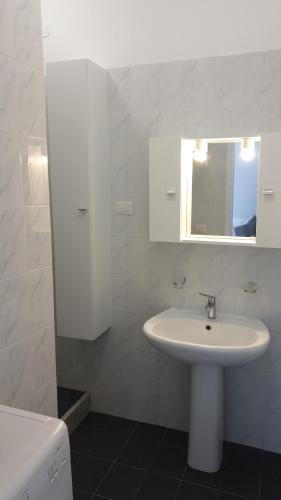 uma casa de banho branca com um lavatório e um espelho em Petra Marina Aurora em Pisciotta