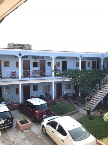een wit gebouw met auto's geparkeerd op een parkeerplaats bij Hotel Izala in San Pedro Pochutla