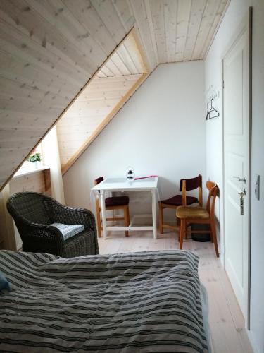 ErslevにあるStenhøj Bed and Breakfast, v. Jette og Mariusのベッド、テーブル、椅子が備わる屋根裏部屋です。