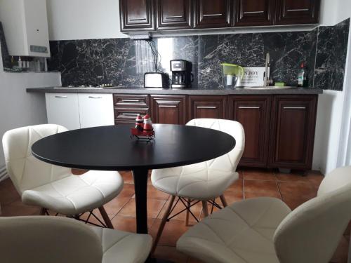 une cuisine avec une table noire et des chaises blanches dans l'établissement Hellen's Ultracentral Apartament, à Buzău