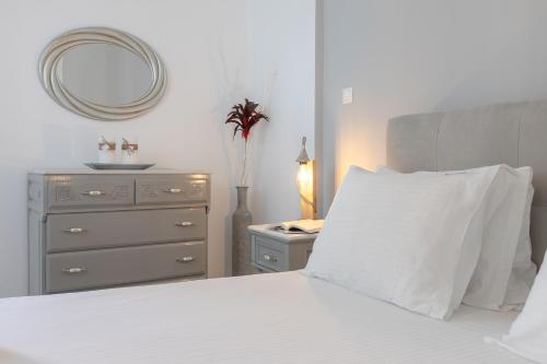 a bedroom with a bed with a dresser and a mirror at NEOKLASSIKO KOUKOULI in Fira