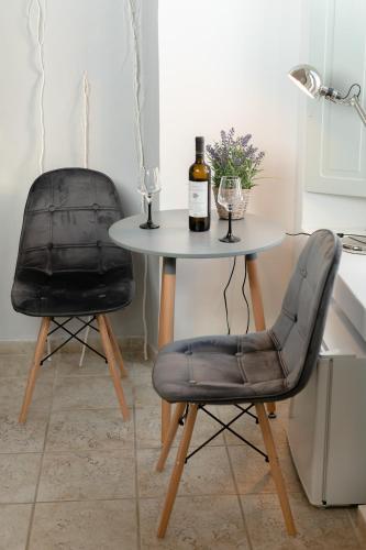 a table with two chairs and a bottle of wine at NEOKLASSIKO KOUKOULI in Fira