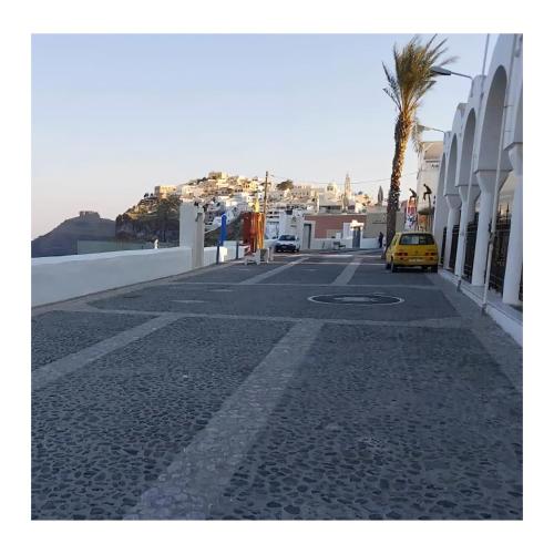 a street with a palm tree and a yellow car at NEOKLASSIKO KOUKOULI in Fira