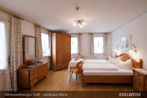 1 dormitorio con 2 camas, escritorio y ventanas en Ferienwohnungen Kröll - Appartements Viktoria und Landhaus Maria, en Mayrhofen