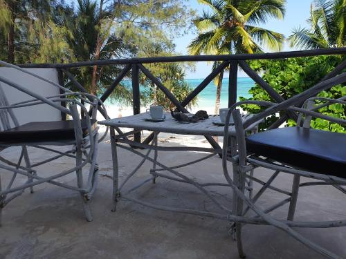a table and chairs on a balcony with the beach at Ayla Beach House in Kiwengwa