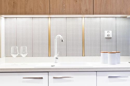 a kitchen with a sink and a wall with tiles at D Apartments Centrum Jurowiecka II in Białystok