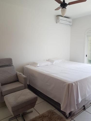 a bedroom with a bed and a chair and a ceiling fan at Casa beira mar Torres in Torres
