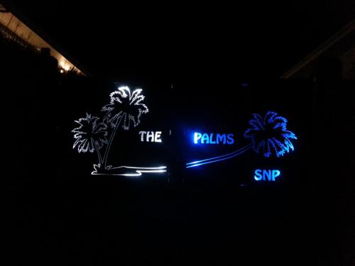 a neon sign with palm trees in the dark at SNP- PALMS in Papetoai