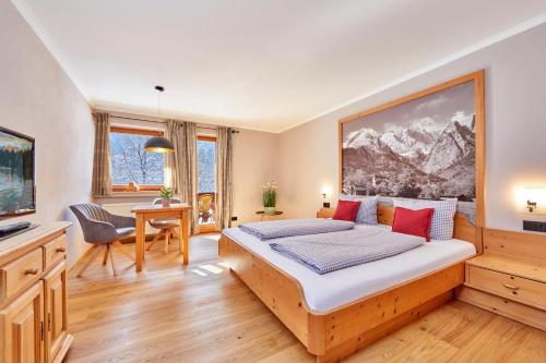 ein Schlafzimmer mit einem Bett mit einem großen Gemälde an der Wand in der Unterkunft Gästehaus Brandnerhof in Garmisch-Partenkirchen