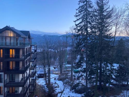 un edificio de apartamentos en invierno con nieve en el suelo en Apartament Snow Sun Szklarska Poręba, en Szklarska Poręba