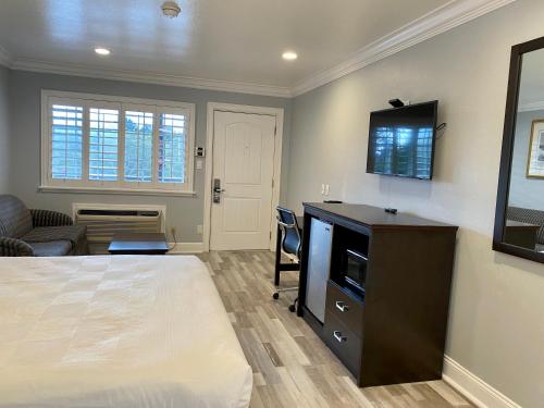 a bedroom with a bed and a desk with a television at Aura Inn Monterey in Monterey
