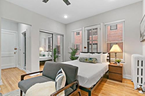 a bedroom with a bed and a chair and windows at Remodeled Studio Apartment in East Lakeview - Barry S1 in Chicago