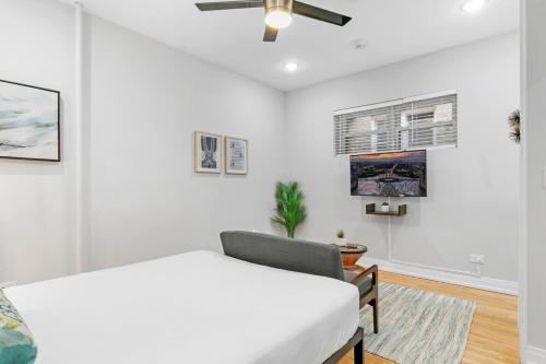 ein weißes Schlafzimmer mit einem Bett und einem Stuhl in der Unterkunft Chic & Updated Studio Apt in East Lakeview - Barry S1 in Chicago