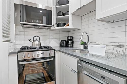 a white kitchen with a stove and a sink at Chic & Updated Studio Apt in East Lakeview - Barry S1 in Chicago