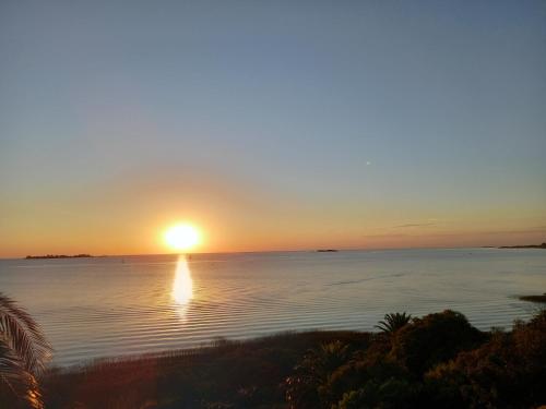 a sunset over the water with the sun setting at Monoambiente en Colonia in Colonia del Sacramento