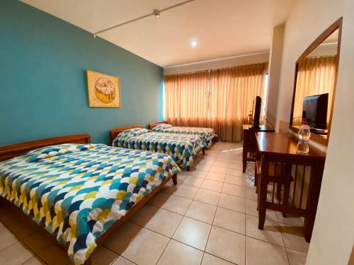 a hotel room with two beds and a desk at Hostal Solar Del Puerto in Machala