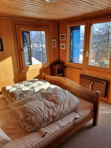 a bedroom with two beds in a room with windows at Chalet Alpina in Riederalp