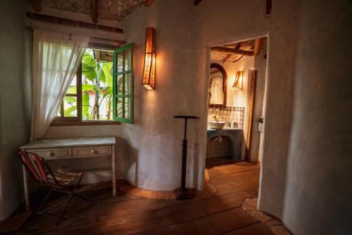 Habitación con escritorio, ventana y silla. en Butterfly House Bahia, en Maraú
