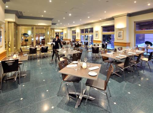 a man walking through a restaurant with tables and chairs at Stamford Plaza Melbourne in Melbourne