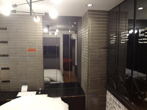 baño con paredes de baldosas grises y espejo en Royal Hotel Uohachi Bettei, en Ōgaki
