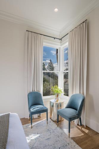 a bedroom with two blue chairs and a window at The George - Luxury Boutique Inn in Napa