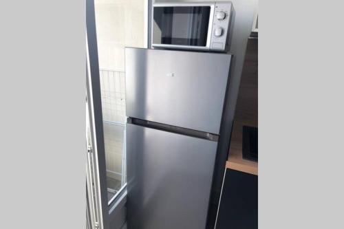 a stainless steel refrigerator with a microwave on top of it at Le Sweet Toulouse Purpan - Hopital & Tram à 5 minutes - Parking in Toulouse