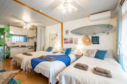 two beds in a room with a surfboard on the wall at Type B Room 27平米 - ウル エスポワール那覇2- in Kume