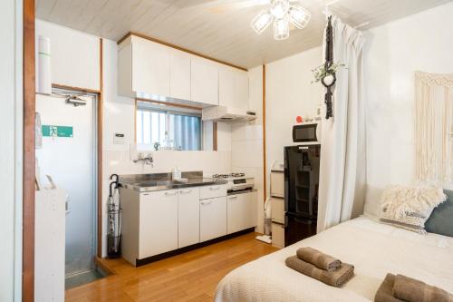 a small kitchen with white cabinets and a bed in a room at Type B Room 27平米 - ウル エスポワール那覇2- in Kume