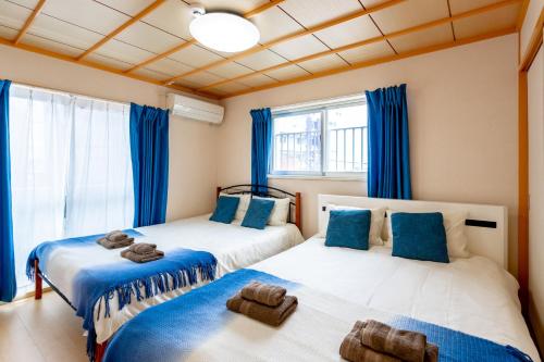 2 Betten in einem Zimmer mit blauen Vorhängen in der Unterkunft Type B Room 40平米 -ウル エスポワール那覇- in Naha