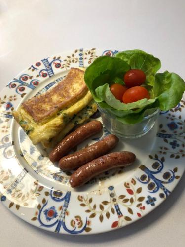 a plate with sausage and a sandwich and a bowl of tomatoes at Casa Khaoyai Bed&Breakfast in Mu Si