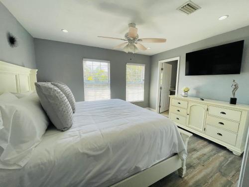 a bedroom with a white bed and a flat screen tv at Sarasota Paradise Heated Pool Home Near IMG & Siesta Key Beach in Sarasota