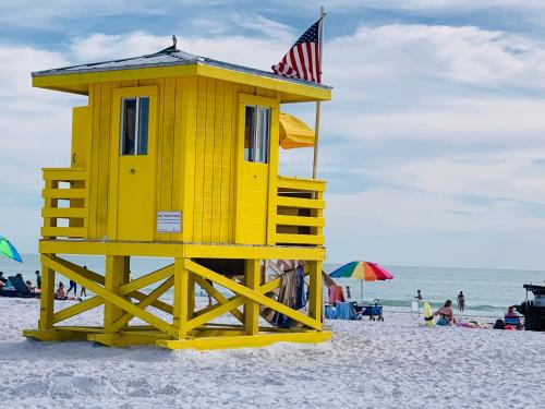 a yellow lifeguard house on a beach with an american flag at Sarasota Paradise Heated Pool Home Near IMG & Siesta Key Beach in Sarasota