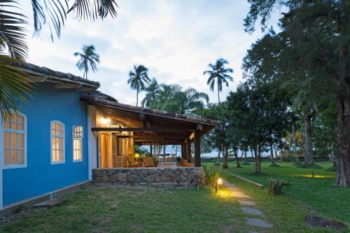 a house with a blue facade and palm trees at Vila Siriúba Hotel in Ilhabela